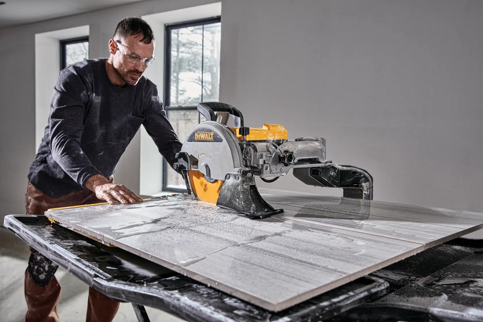 A DEWALT-branded tile saw with a yellow and silver cutting blade, mounted on a foldable black stand with an extended work surface.