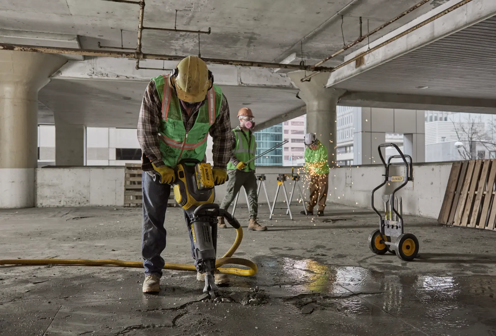 Trabajadores usan herramientas DEWALT en construcción, como martillo demoledor y carrito de equipo.