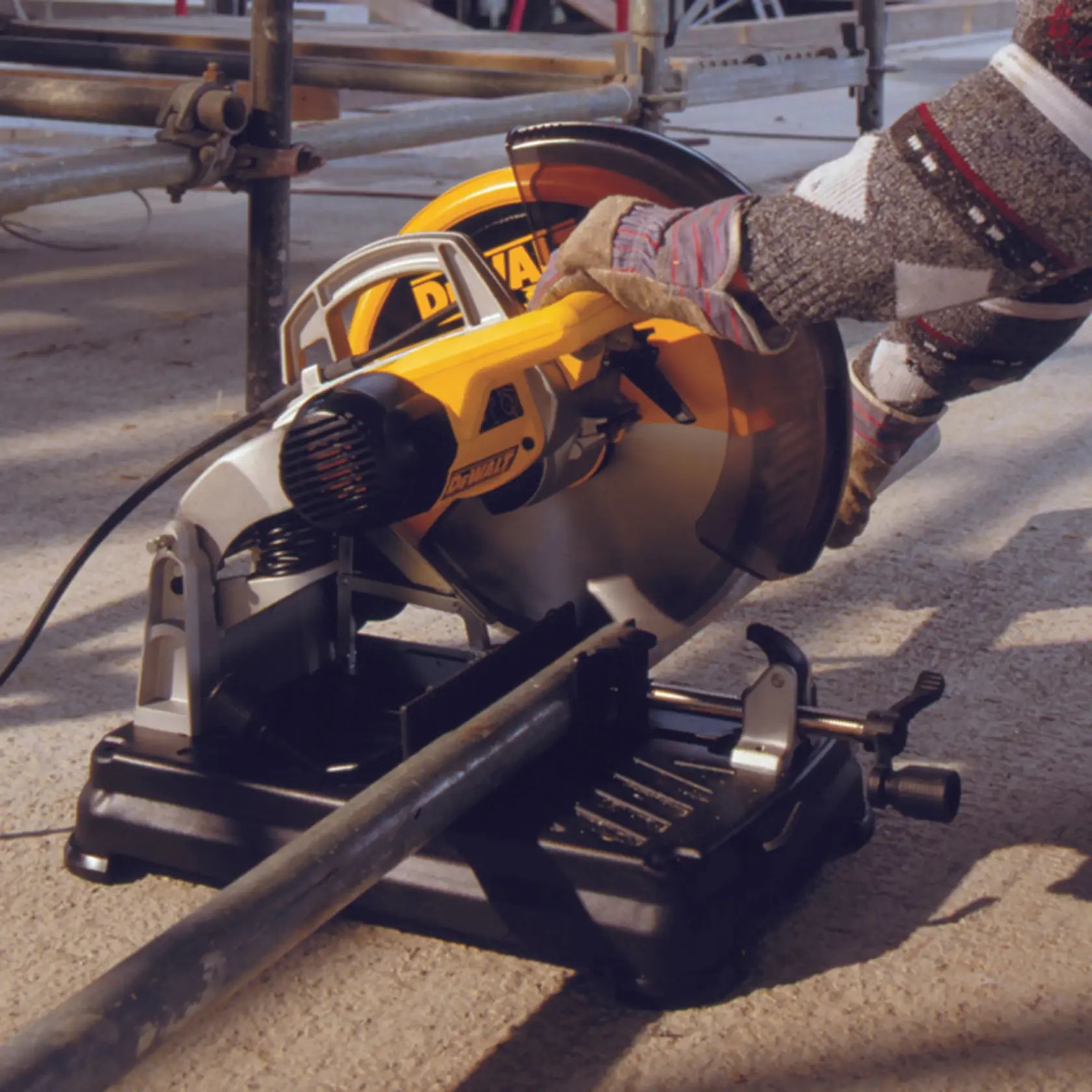 Sierra circular DEWALT DT1921 cortando tubo metálico, accionada por mano enguantada en obra.