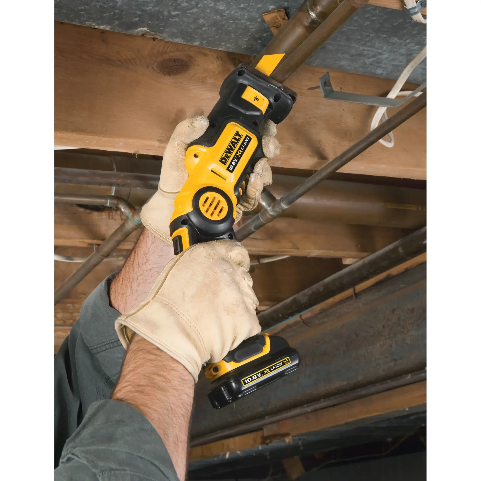 Behandschuhte Hände schneiden mit einer DEWALT Akku-Säbelsäge ein Rohr an der Decke.