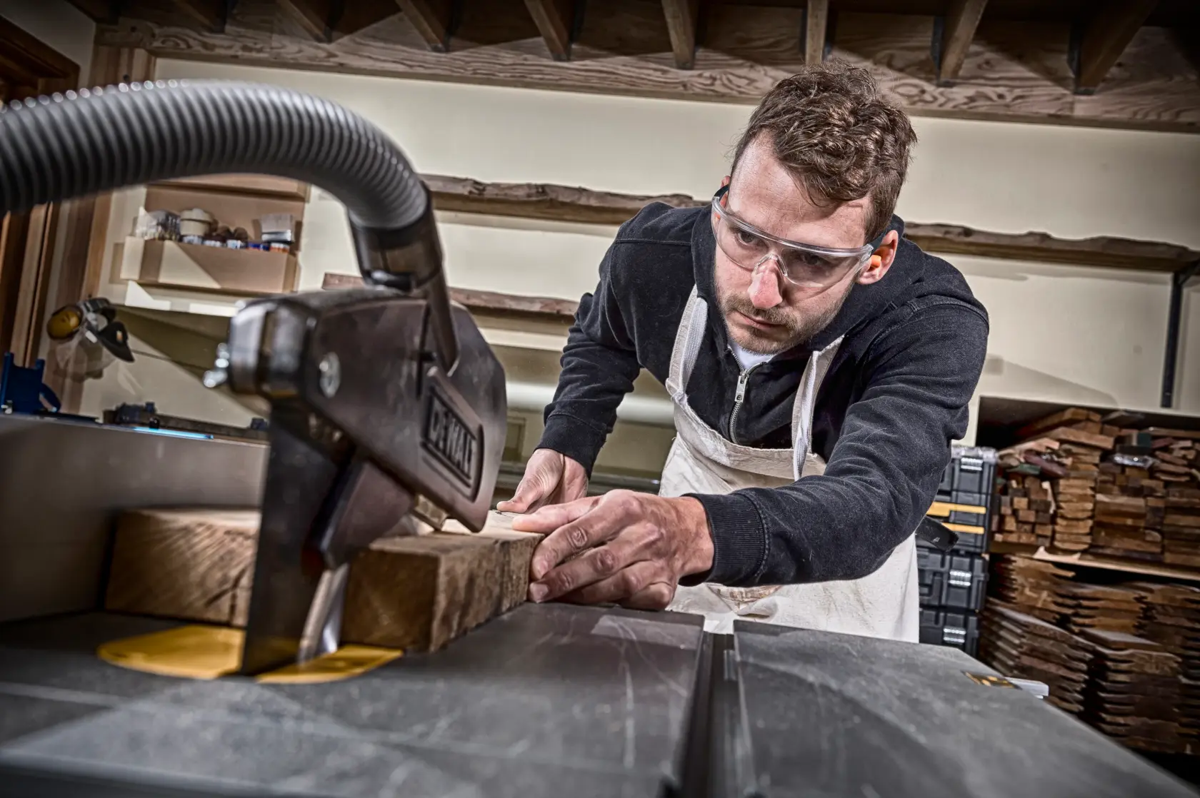 Persona cortando madera con una máquina DEWALT en taller; rostro difuminado para privacidad.