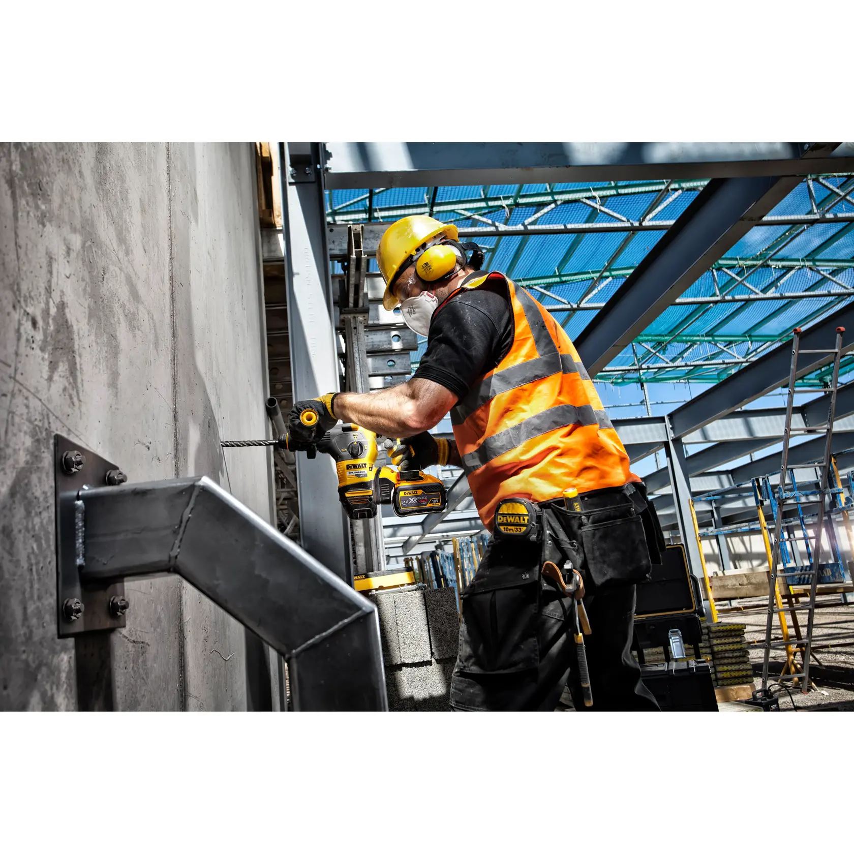 Trabajador perfora pared de concreto con herramienta DEWALT en obra, lleva equipo de seguridad y chaleco naranja.
