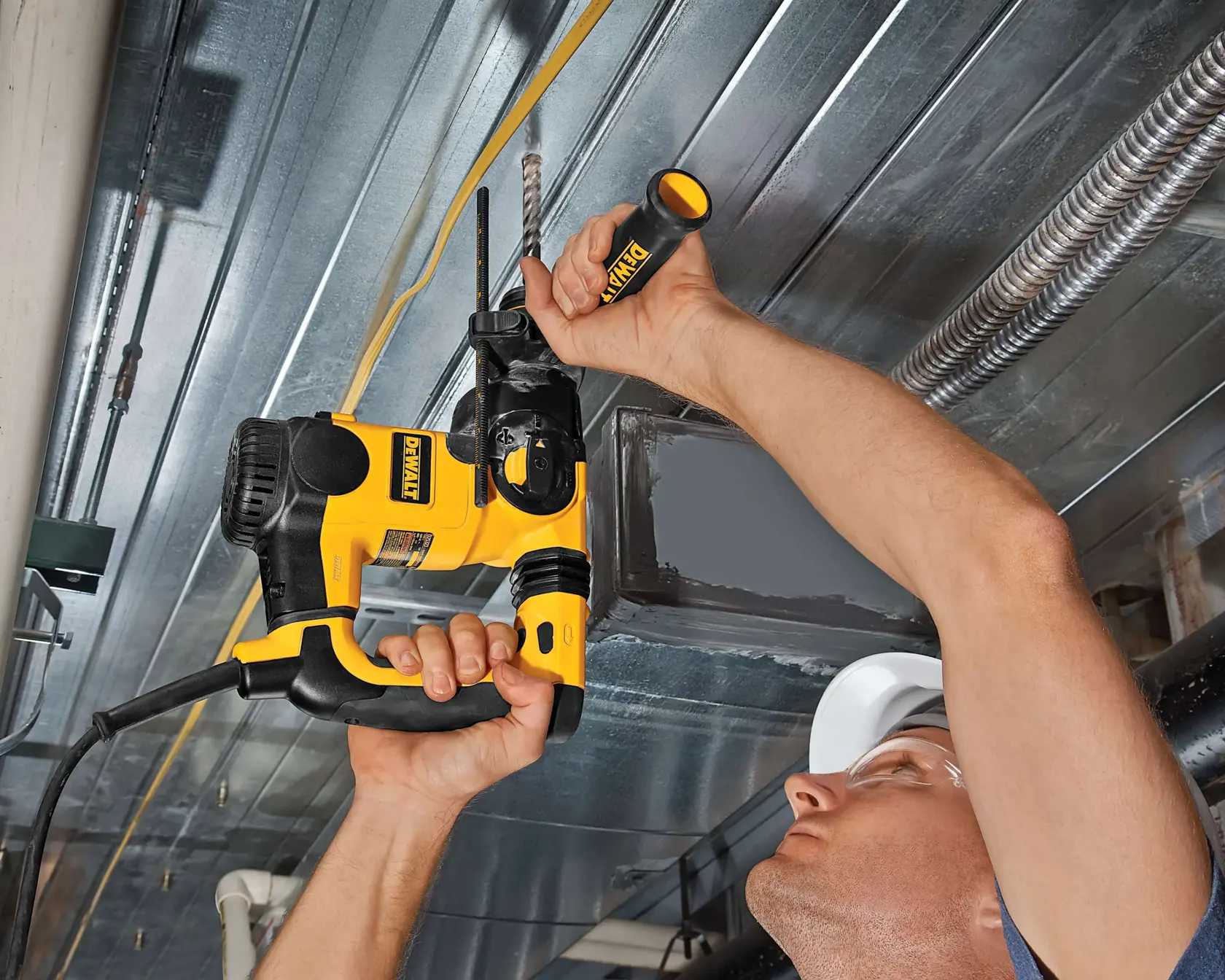 Persona perfora un techo de metal usando herramienta eléctrica DEWALT amarilla y negra con mango lateral.