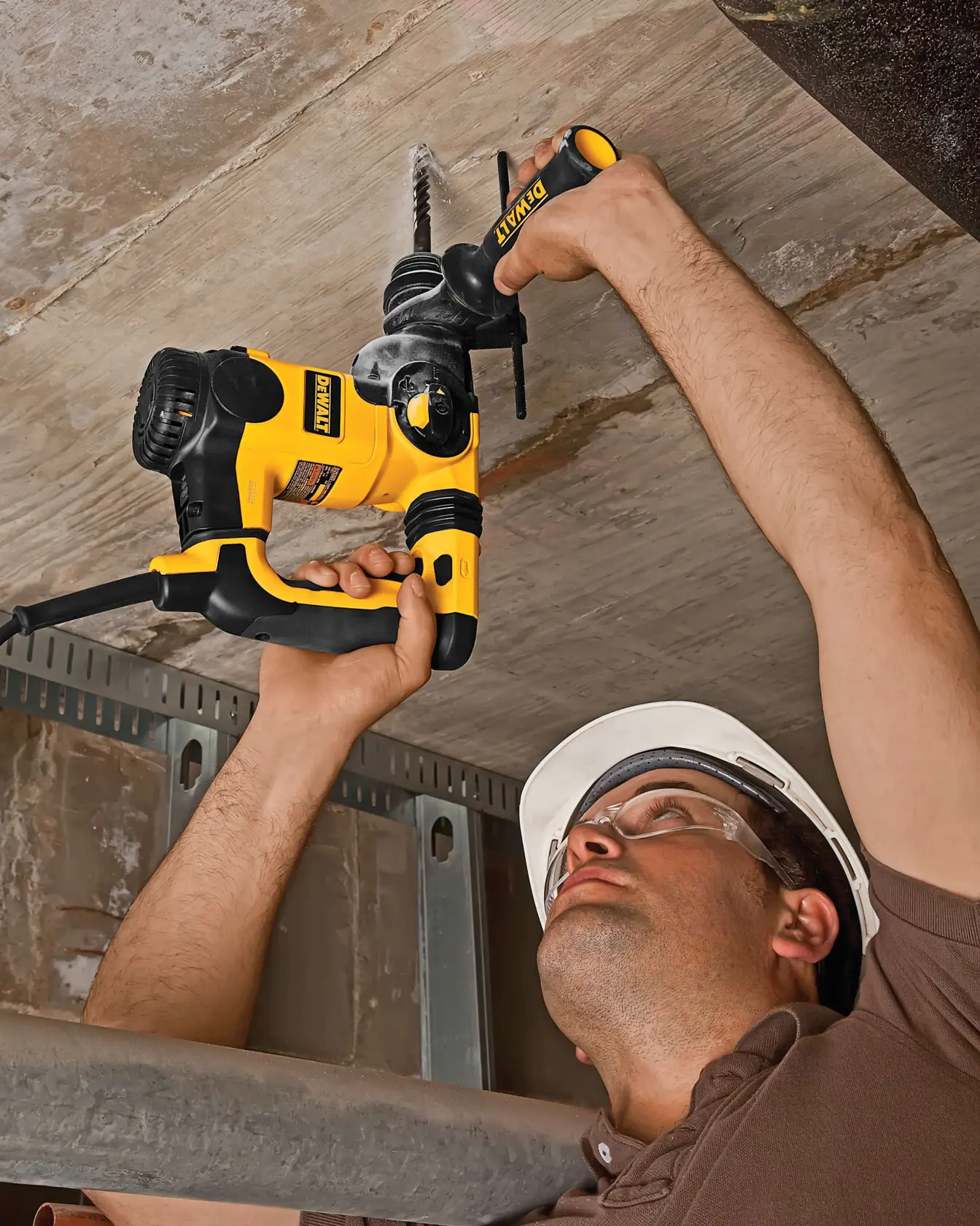 Persona perfora el techo con taladro amarillo DEWALT, herramienta utilizada en tareas de construcción.